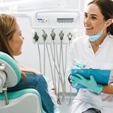 Dentist smiling while taking notes on clipboard