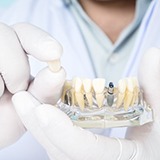 La Porte implant dentist holding dental implant restoration