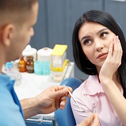 woman in pink shirt with toothache at emergency dentist in La Porte