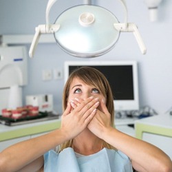 A woman covering her mouth at the dentist.