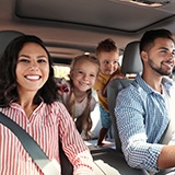 Parents in La Porte smiling with kids in car after teeth whitening
