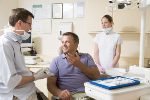 Man in dental chair talking to dentist