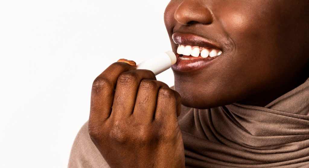 woman applying lip balm to prevent winter mouth issues in La Porte