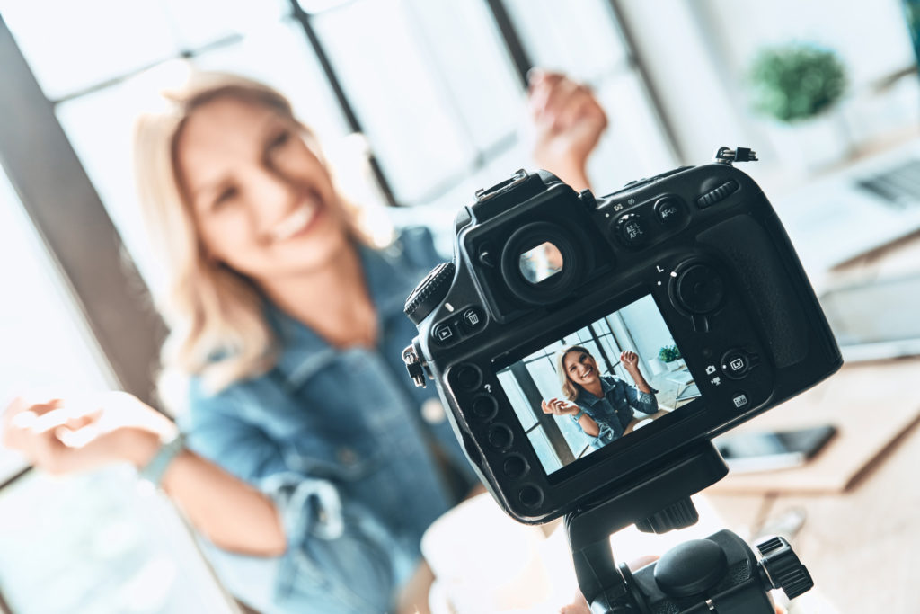 person smiling while being recorded by camera